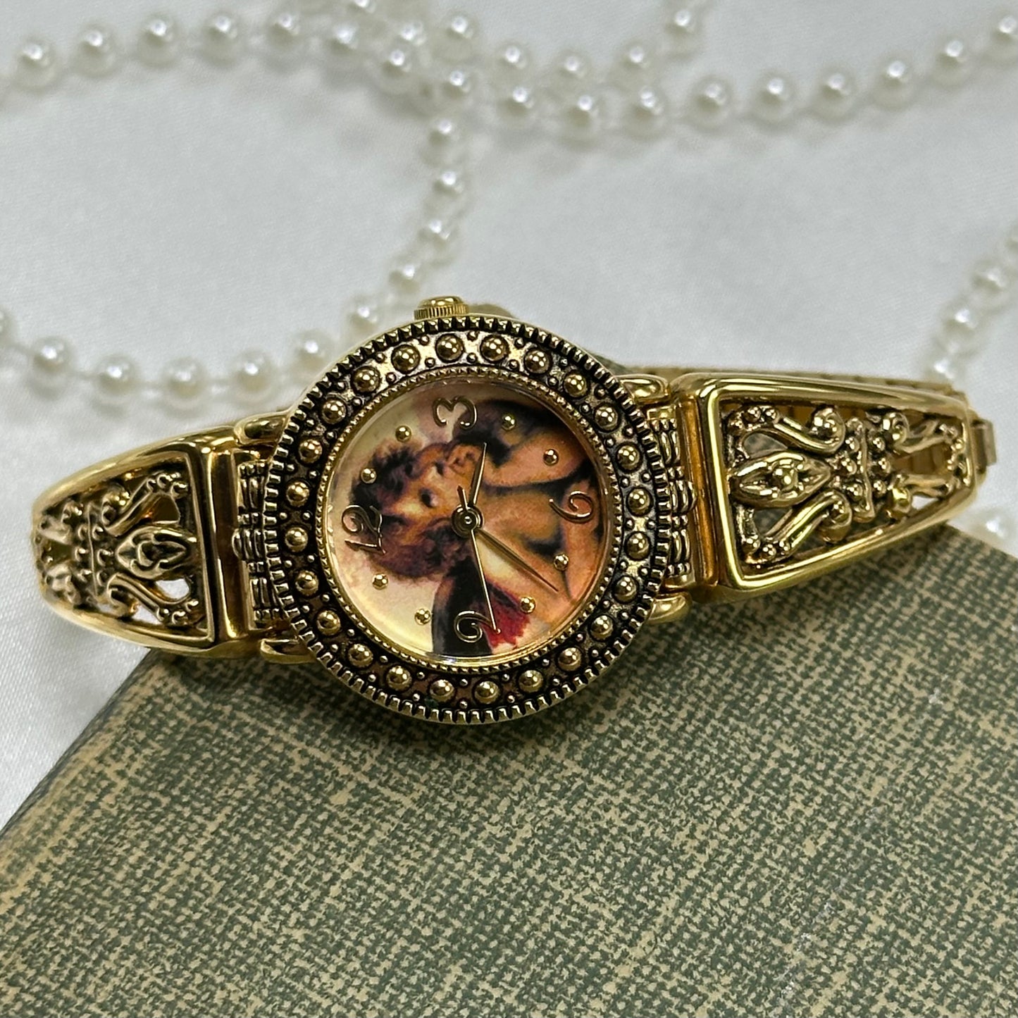 Vintage gold tone Cherub watch with stretchable band and quartz movement.