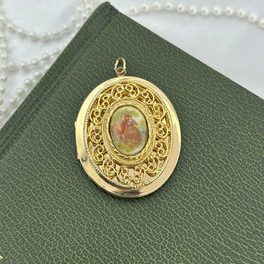 Vintage gold tone Fragonard couple oval filigree locket pendant ft. a Victorian style painted cameo of lovers.