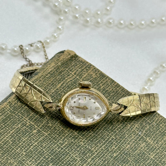 Vintage gold tone Helbros manual winding watch with detailed clasp band and safety chain. Watch comes with original H crown.