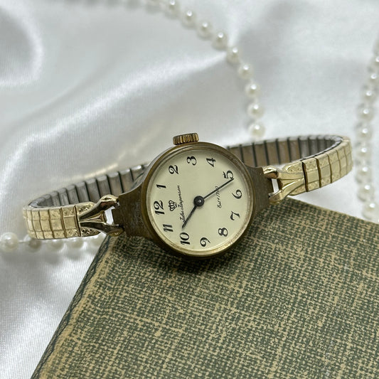 Vintage gold tone Jules Jurgensen manual winding watch with round dial and detailed stretchable band.