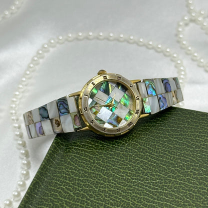 Vintage gold tone LA Express watch with round checkered abalone dial, roman numeral markers, and stretchable band.
