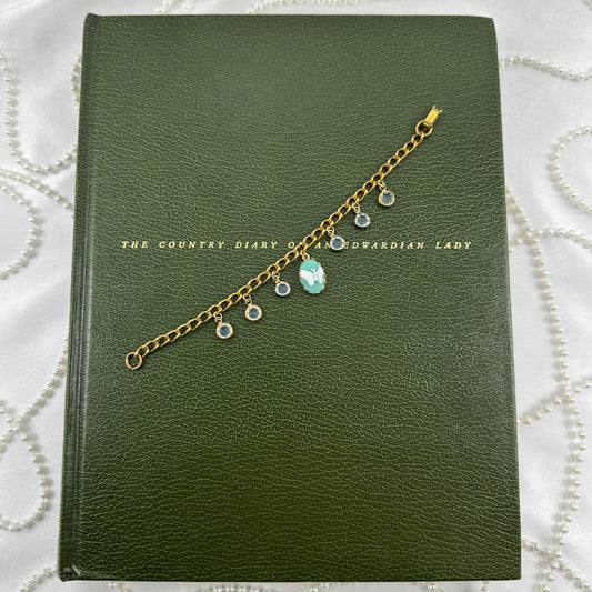 Vintage gold tone Sarah Coventry chain bracelet with light blue glass charms and added blue butterfly cameo.