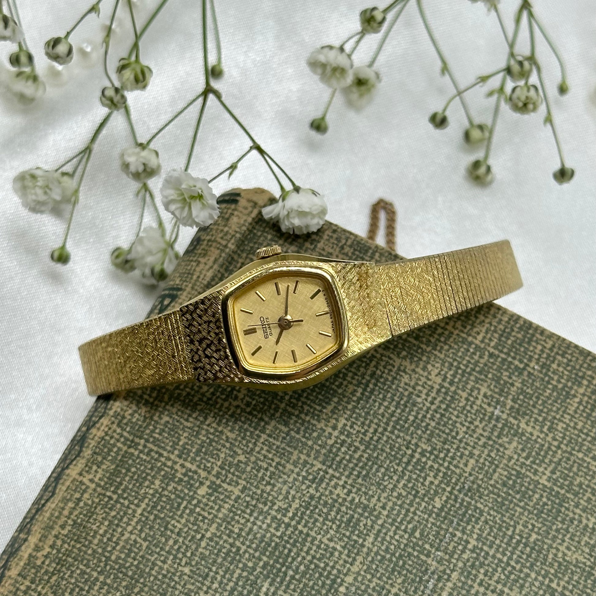 Vintage gold tone Seiko watch with quartz movement and clasp band.