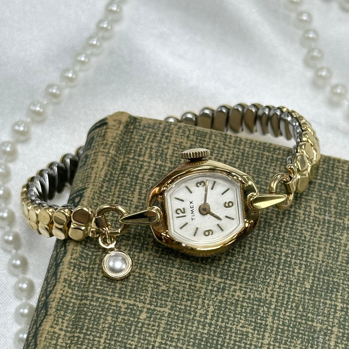 Vintage gold tone Timex manual winding cocktail watch with unique stretchable band and dainty faux pearl charm.