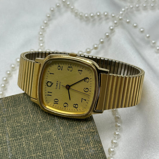 Vintage gold tone Timex watch with quartz movement and stretchable band.