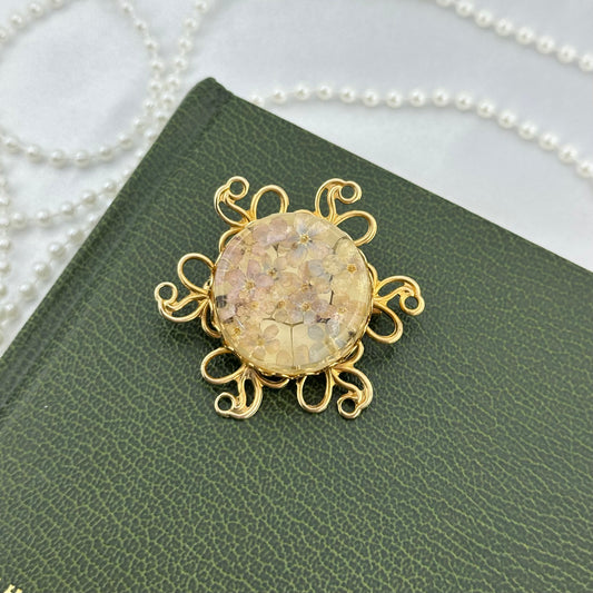 Vintage gold tone circle brooch pin with pressed flowers inside and metal petals.