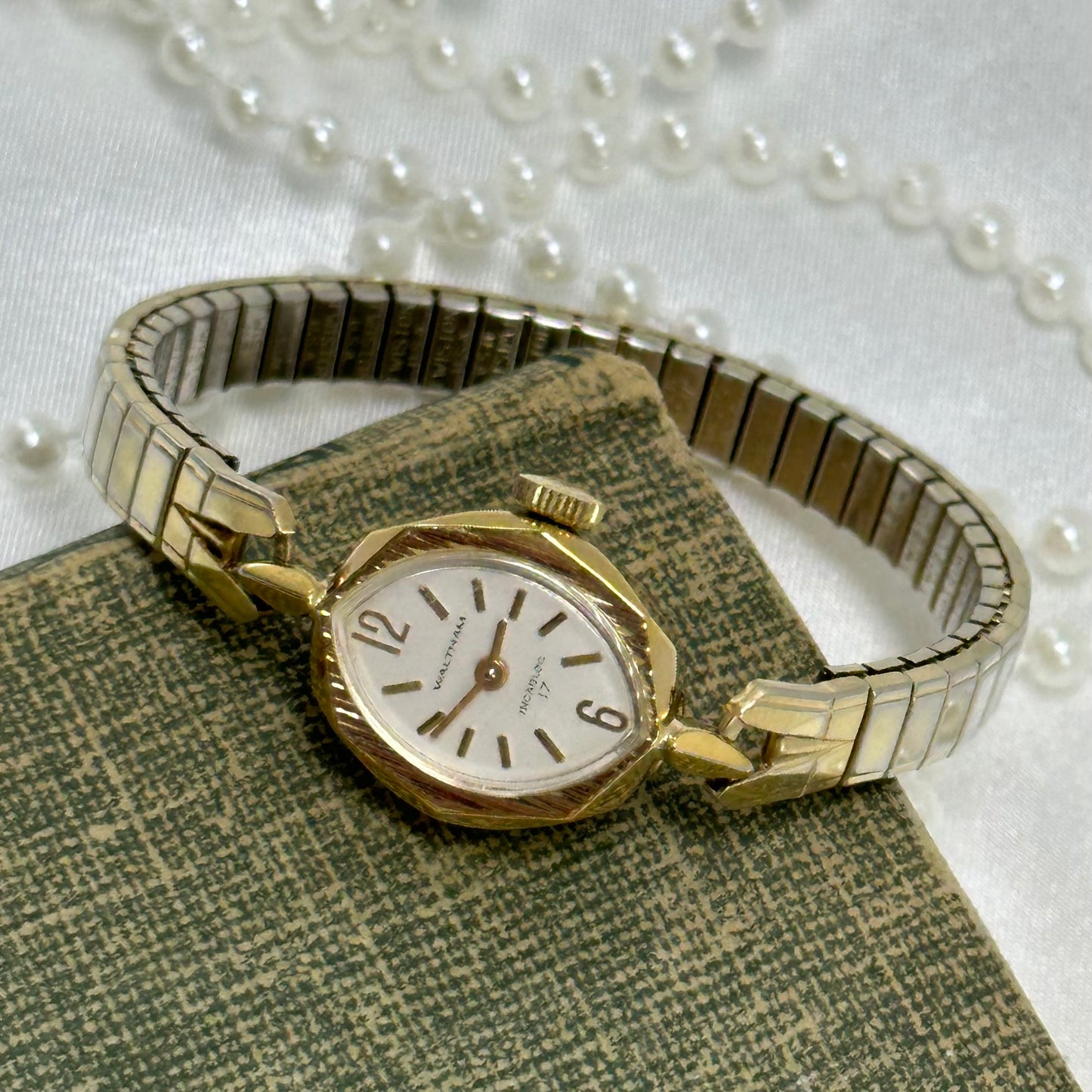 Vintage gold tone dainty Waltham Incabloc 17 manual winding cocktail watch with detailed bezel and stretchable band