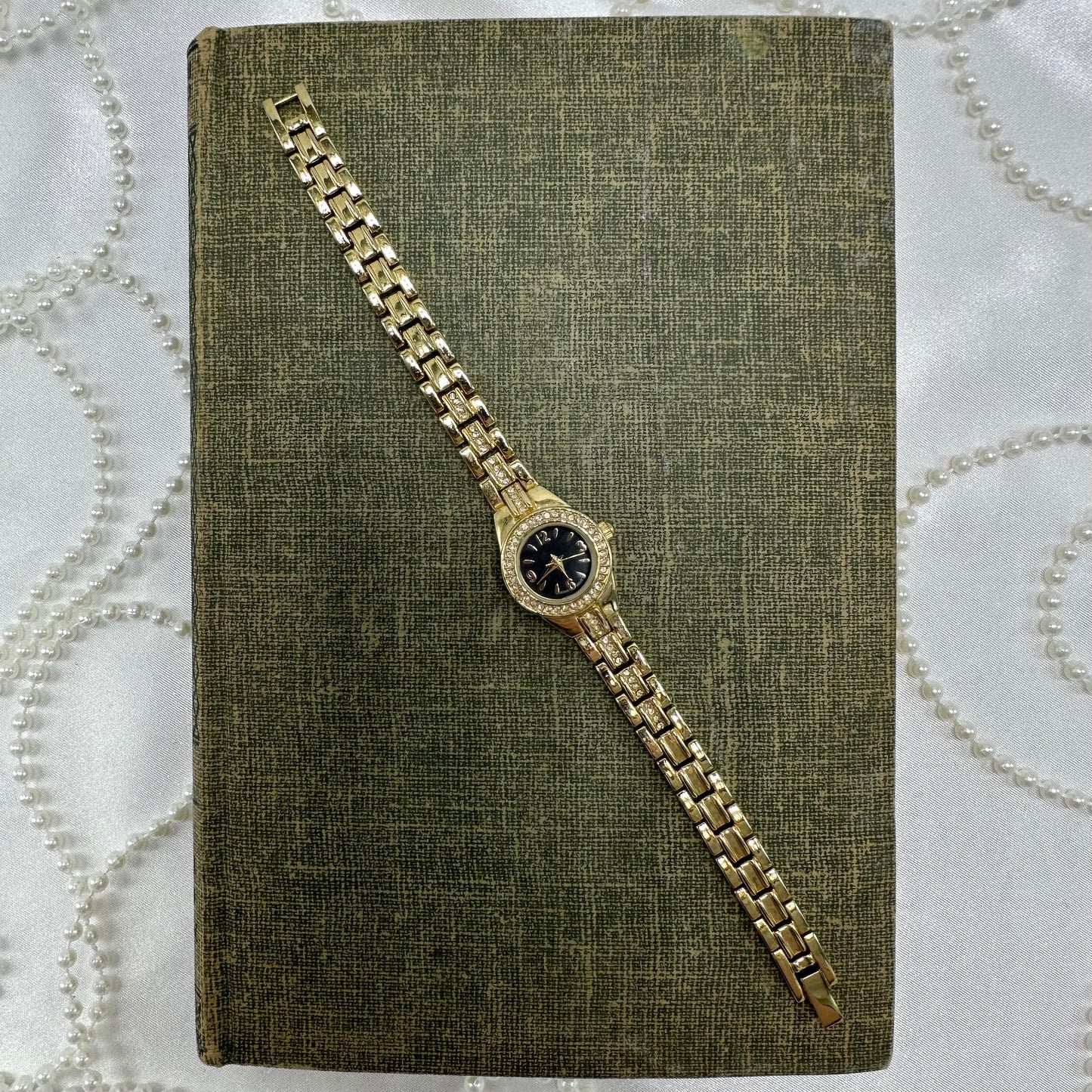 Vintage gold tone diamanté watch with round black dial and quartz movement.