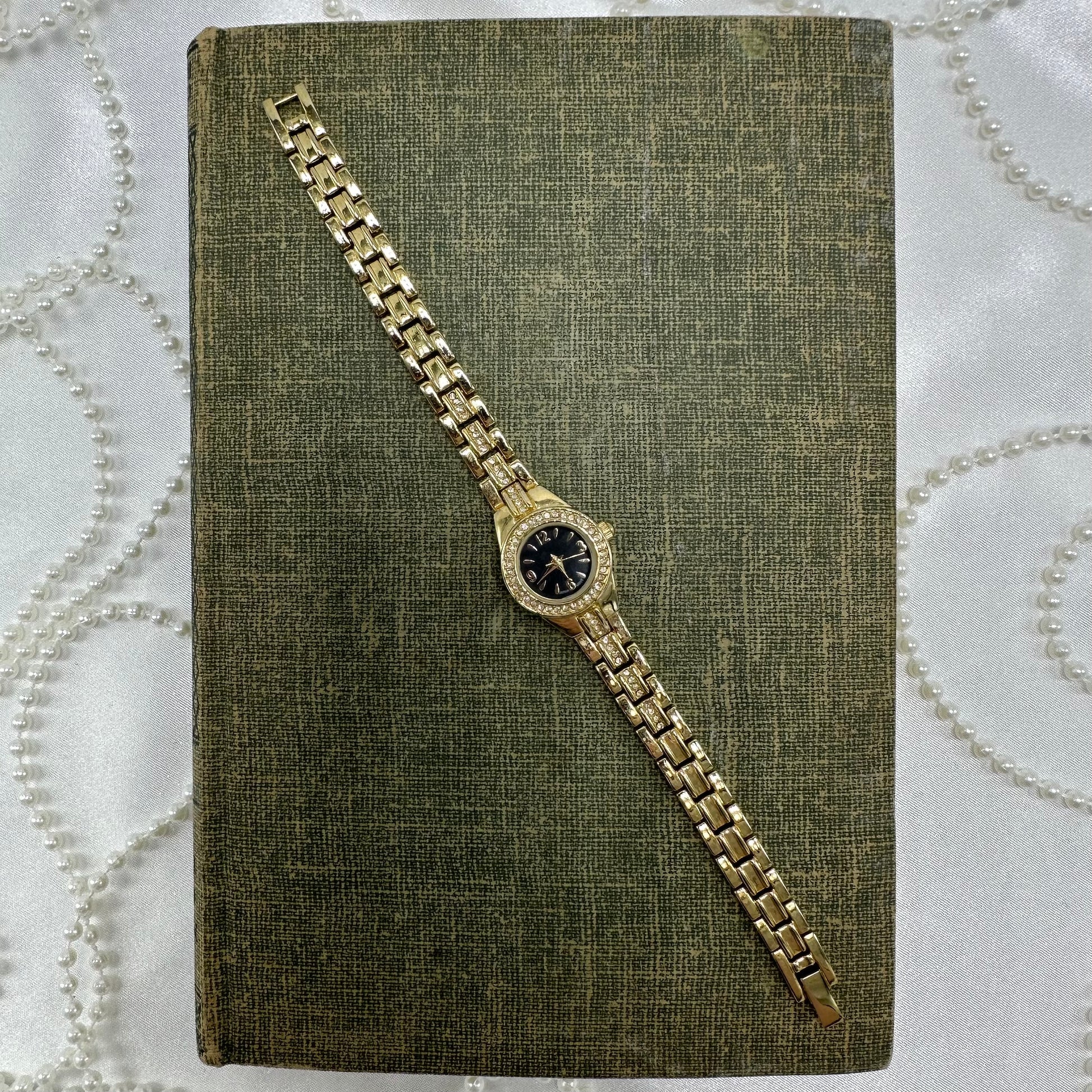 Vintage gold tone diamanté watch with round black dial and quartz movement.