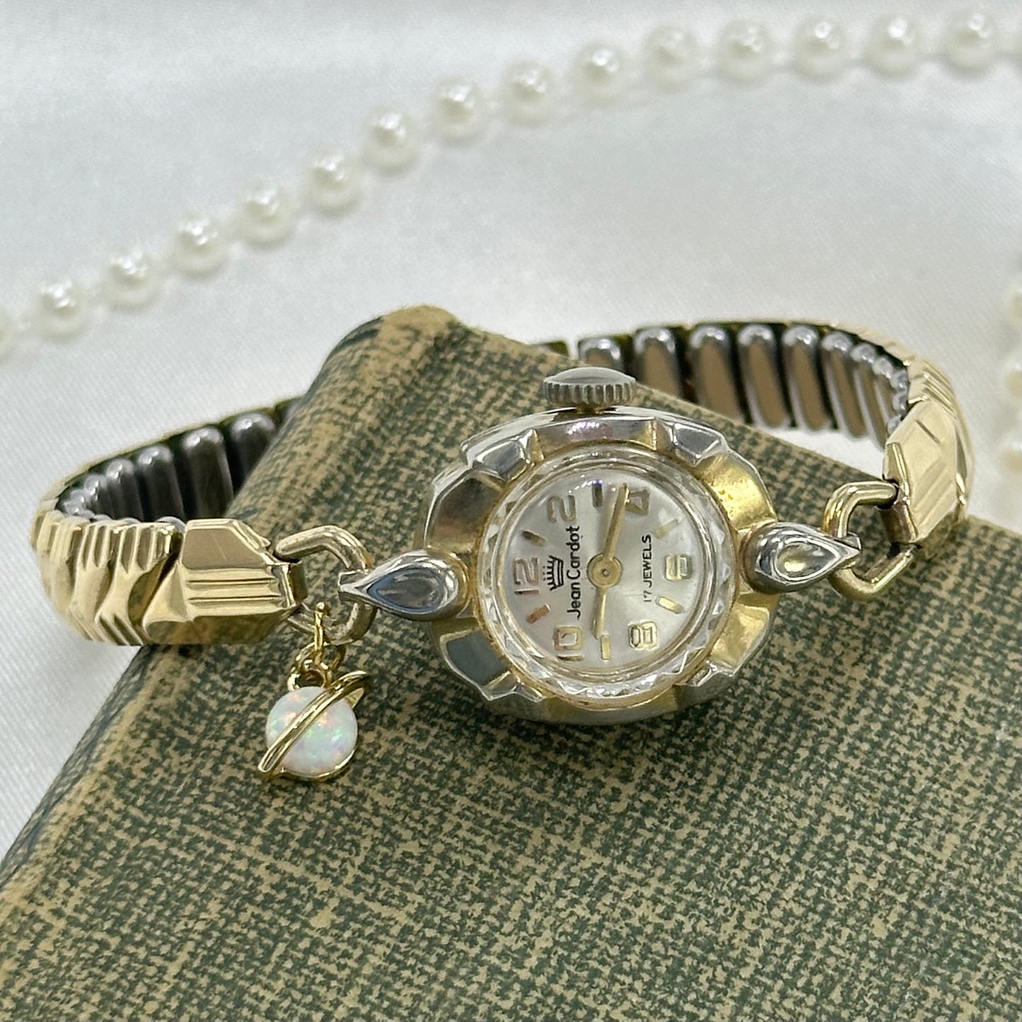 Vintage gold tone manual winding Jean Cardot 17 jewels watch with stretchable band and faux opal Saturn charm.