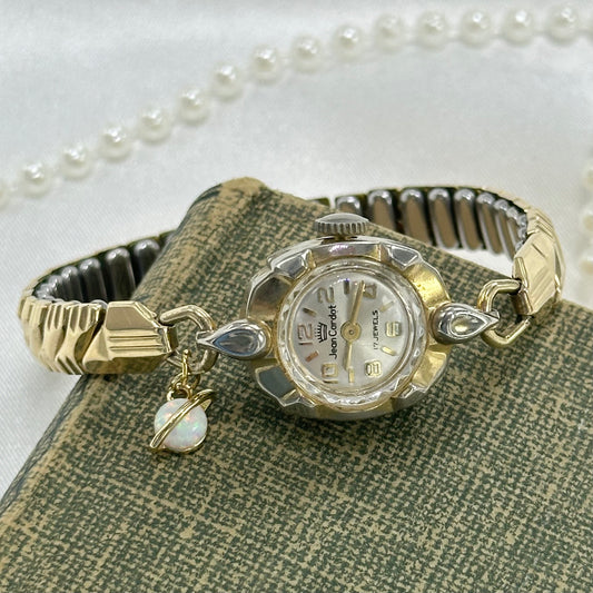 Vintage gold tone manual winding Jean Cardot 17 jewels watch with stretchable band and faux opal Saturn charm.