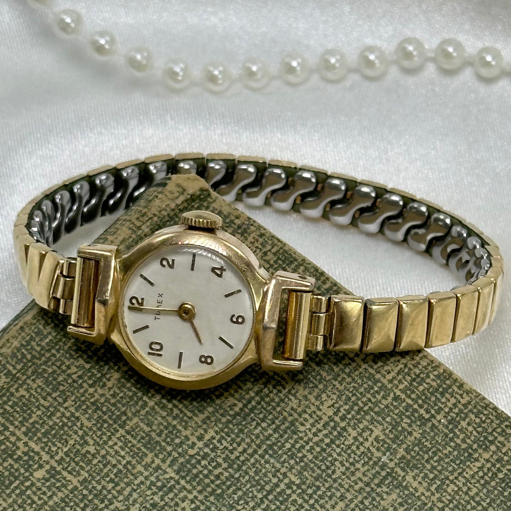 Vintage gold tone manual winding Timex watch with round dial and stretchable band.