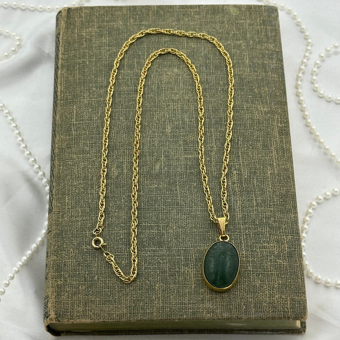 Vintage gold tone necklace with green scarab pendant on braided rope chain.