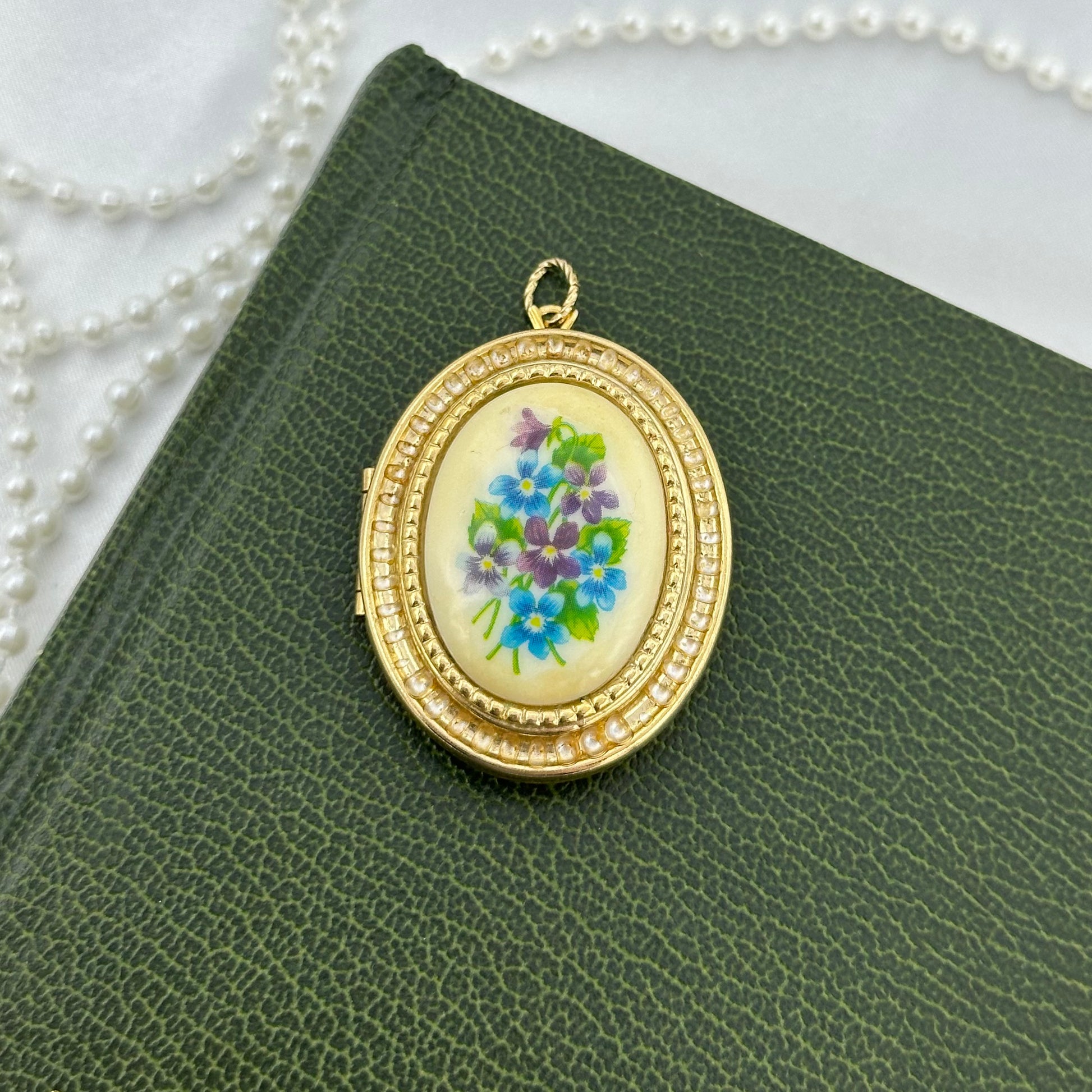 Vintage gold tone oval hanging photo locket by Avon with gorgeous blue and purple floral decal.