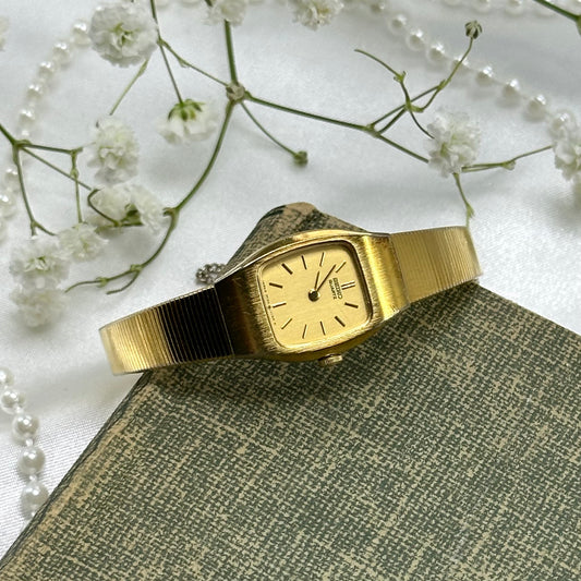 Vintage gold tone square dial Seiko watch with quartz movement and clasp band.