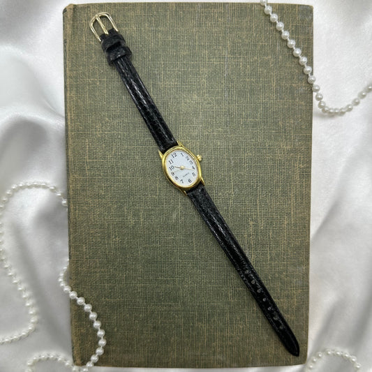 Vintage gold tone watch with quartz movement and faux leather band.