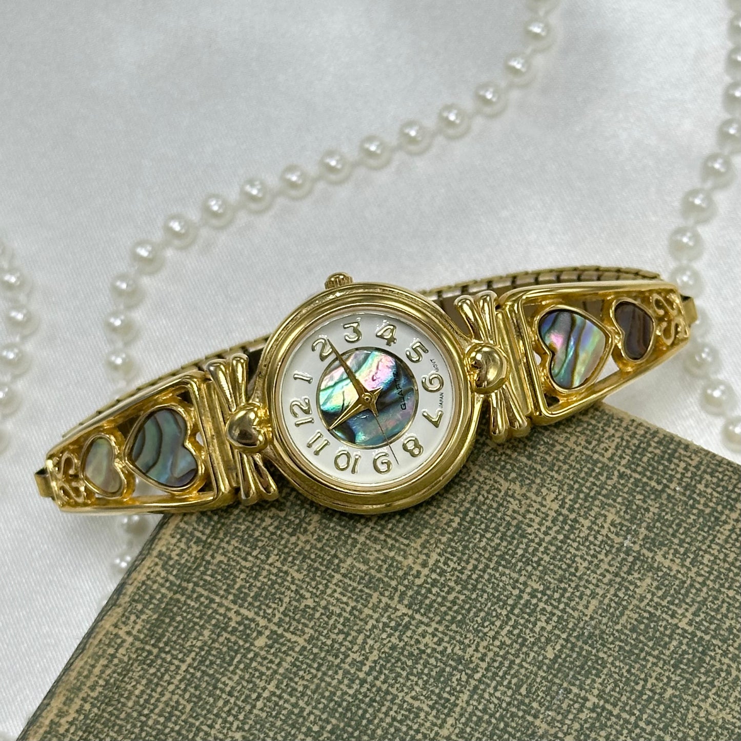 Vintage gold tone watch with round abalone dial and abalone heart stretchable band.