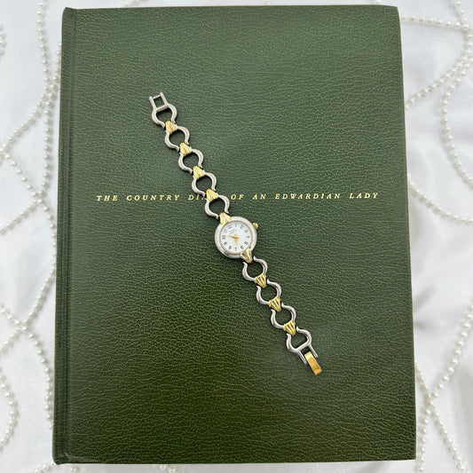 Vintage silver and gold tone Anne Klein II watch with quartz movement and clasp band.