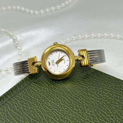 Vintage silver and gold tone Anne Klein watch with hinged bangle band and round dial.