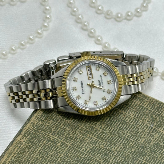 Vintage silver and gold tone Armitron tank watch with date display and metal clasp band. Water resistant. Crystal markers and luminous hands.