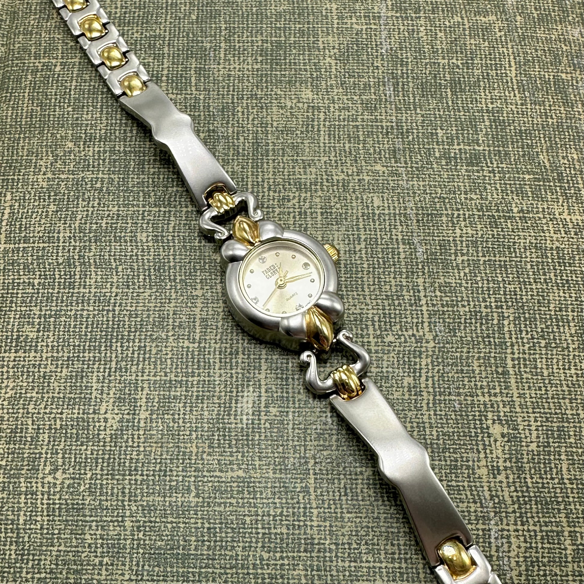 Vintage silver and gold tone Faded Glory watch with round dial and unique band.
