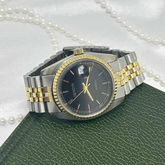 Vintage silver and gold tone Geneva watch with round black dial, date display and fold over clasp band.