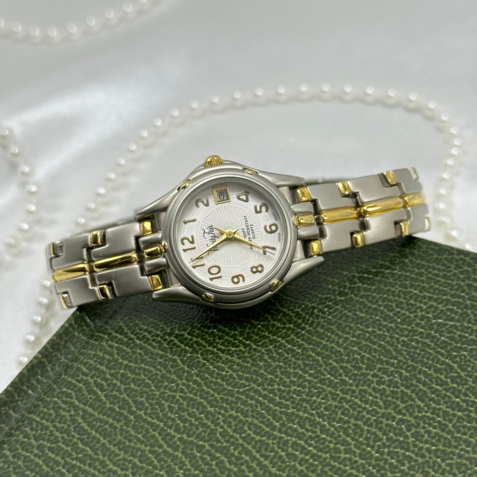 Vintage silver and gold tone Vanity fair tank watch with round dial, date display, and fold over clasp band.