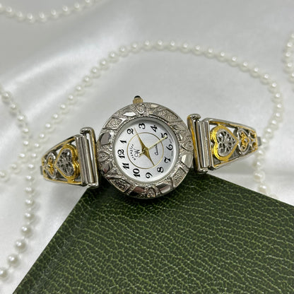 Vintage silver and gold tone Wrangler watch with round dial, two-tone filigree stretchable band, and black jewel crown.