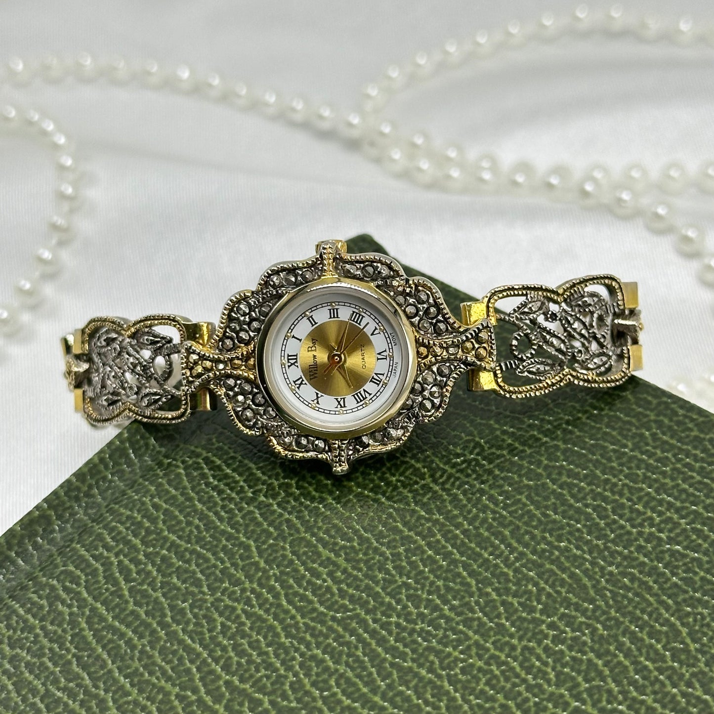 Vintage silver and gold tone art deco style watch with intricate intwined band and roman numeral markers.