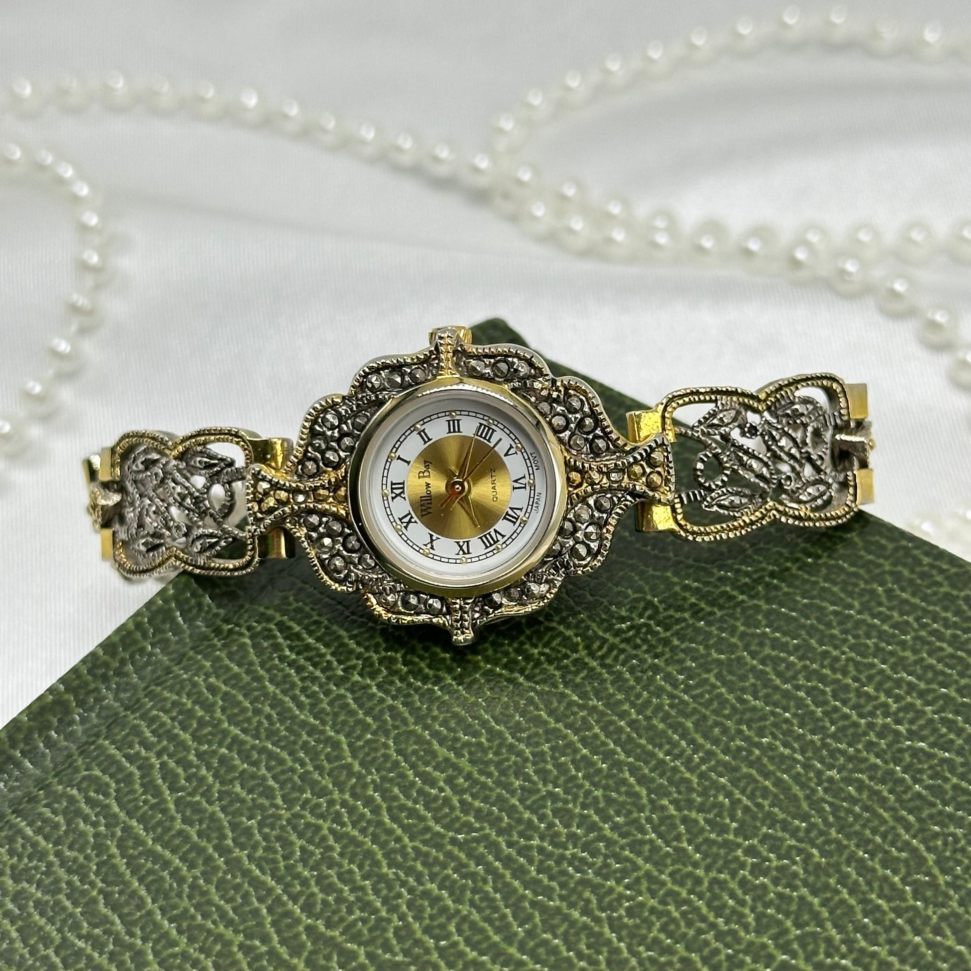 Vintage silver and gold tone art deco style watch with intricate intwined band and roman numeral markers.