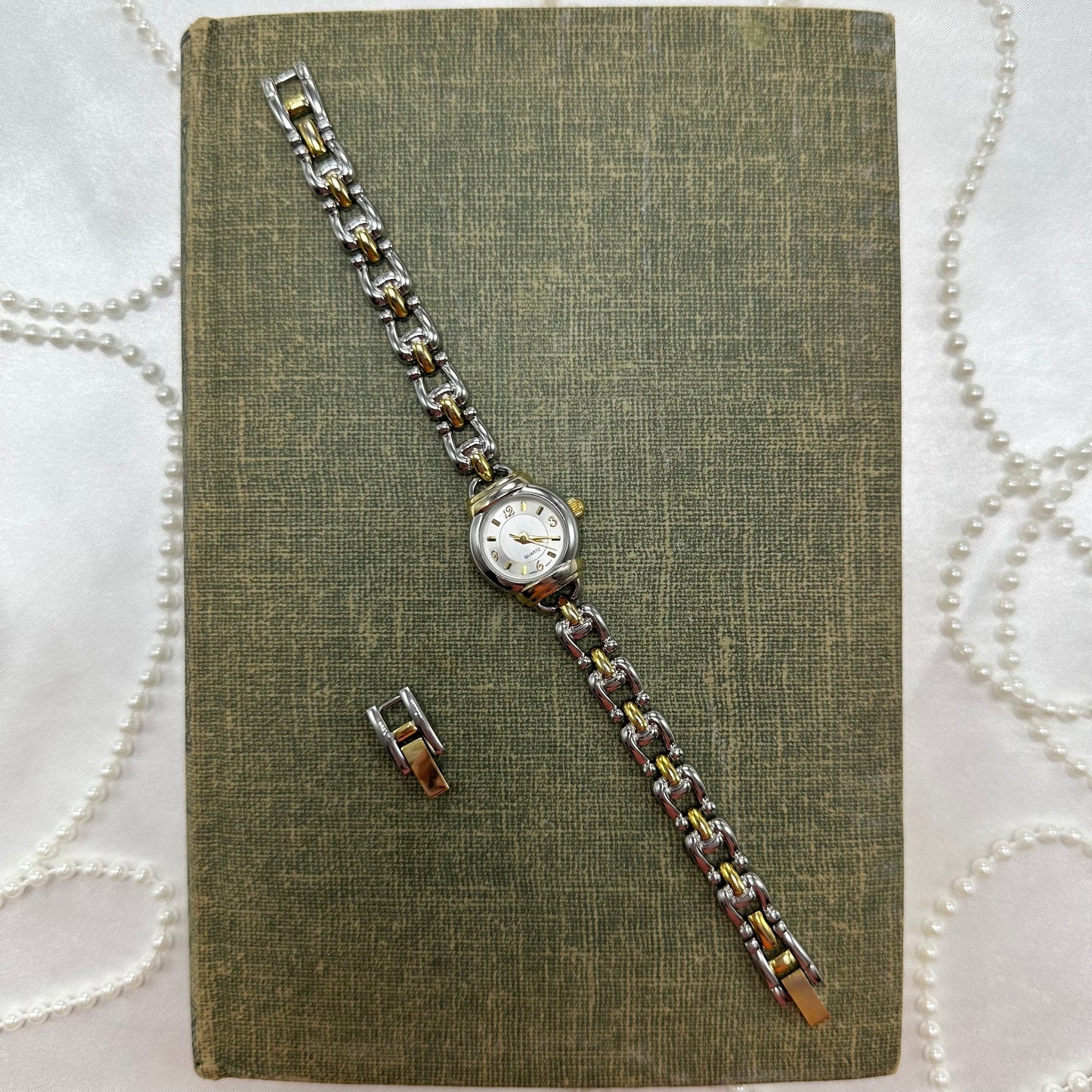 Vintage silver and gold tone round dial watch with dainty chain band and quartz movement.