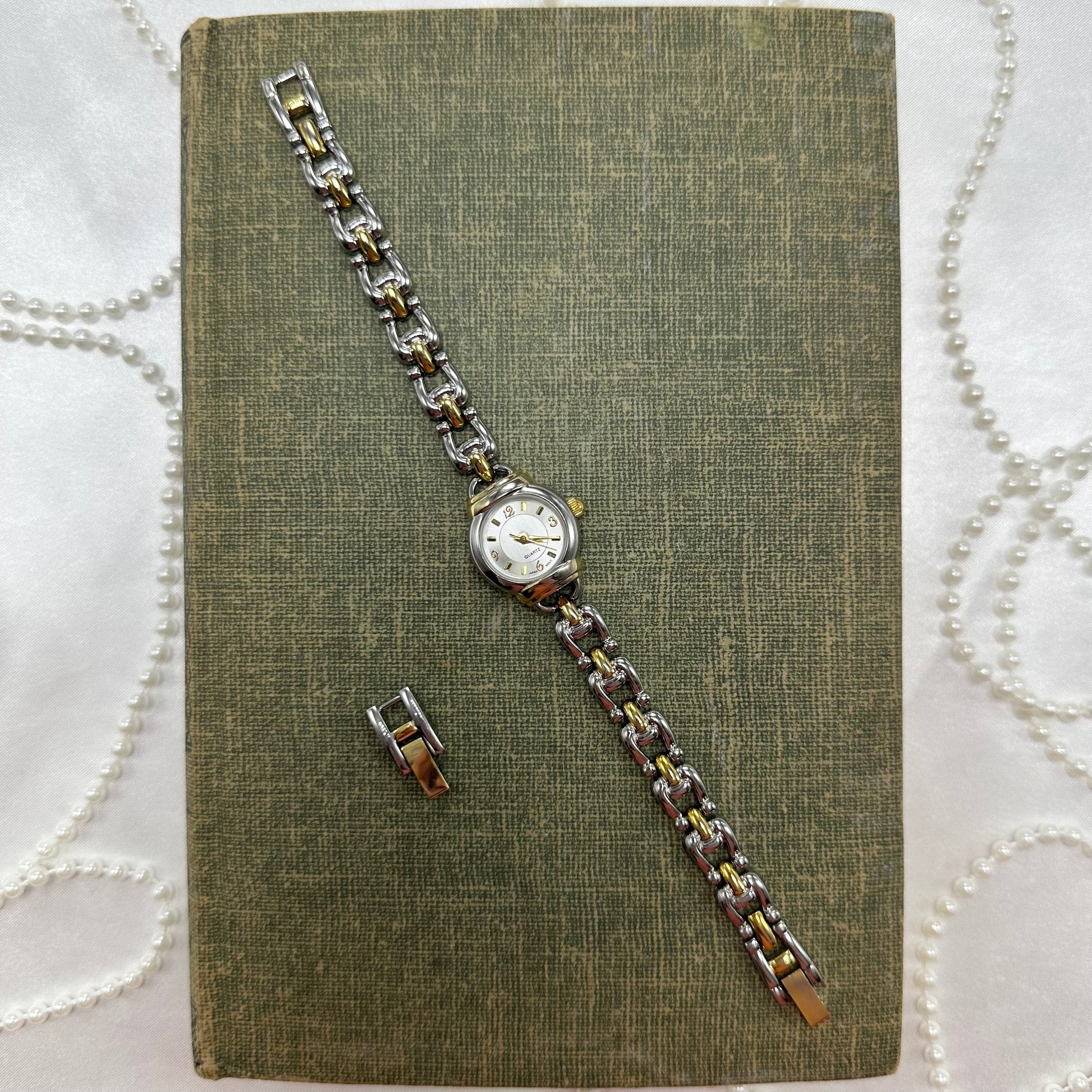 Vintage silver and gold tone round dial watch with dainty chain band and quartz movement.