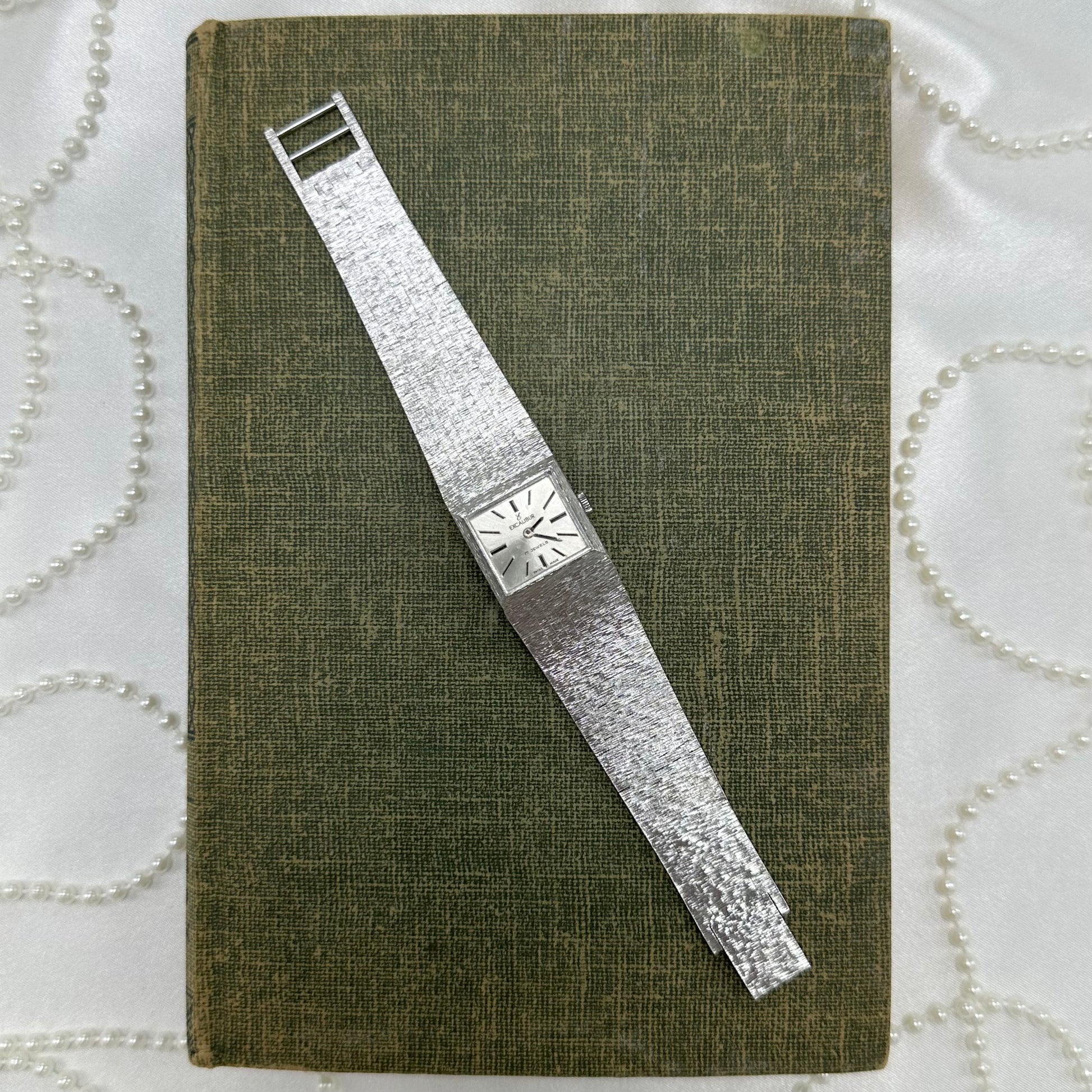 Vintage silver tone 17 jewels Swiss made, manual winding Excalibur tank watch with square dial and textured clasp band.