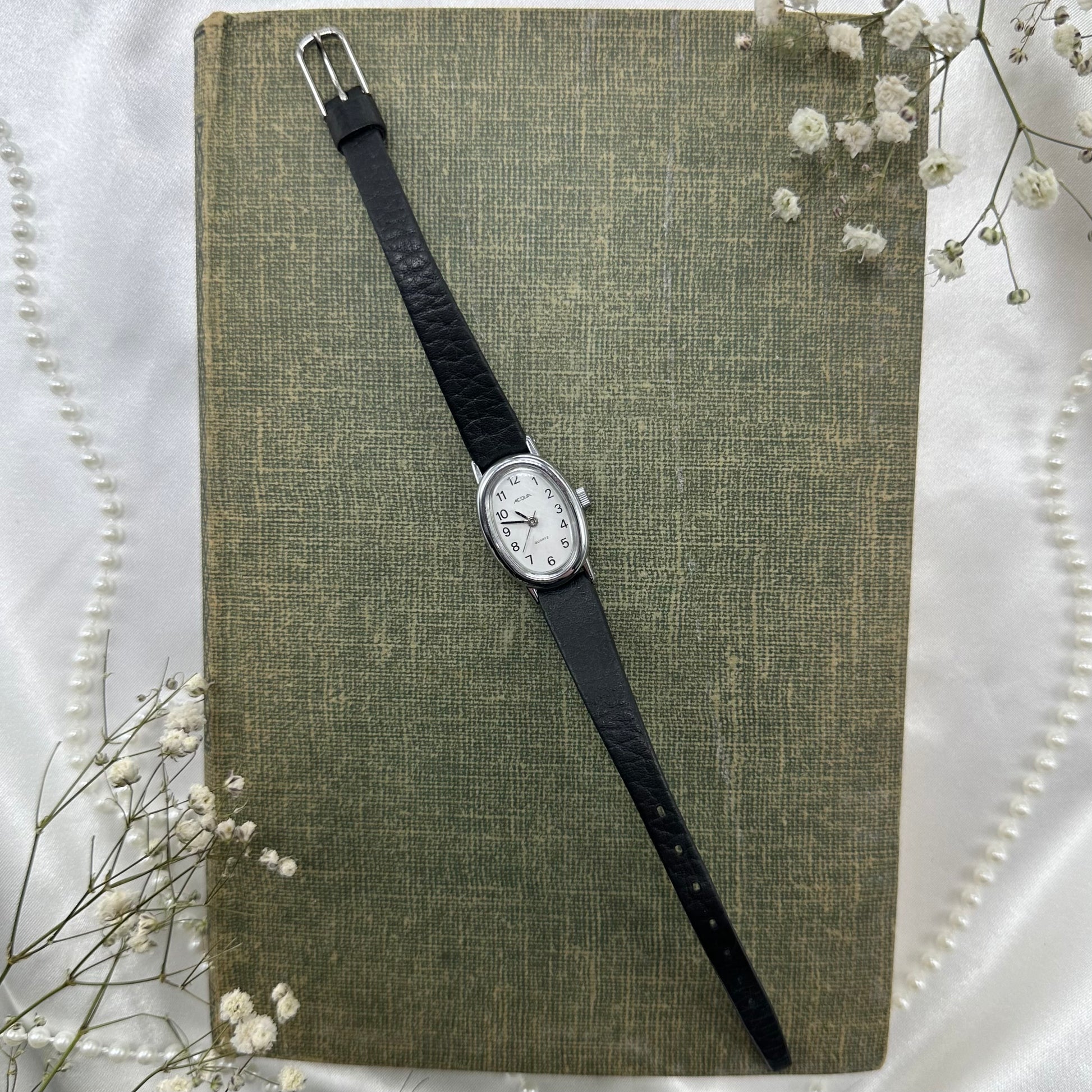 Vintage silver tone Acqua watch with slender black band and quartz movement.
