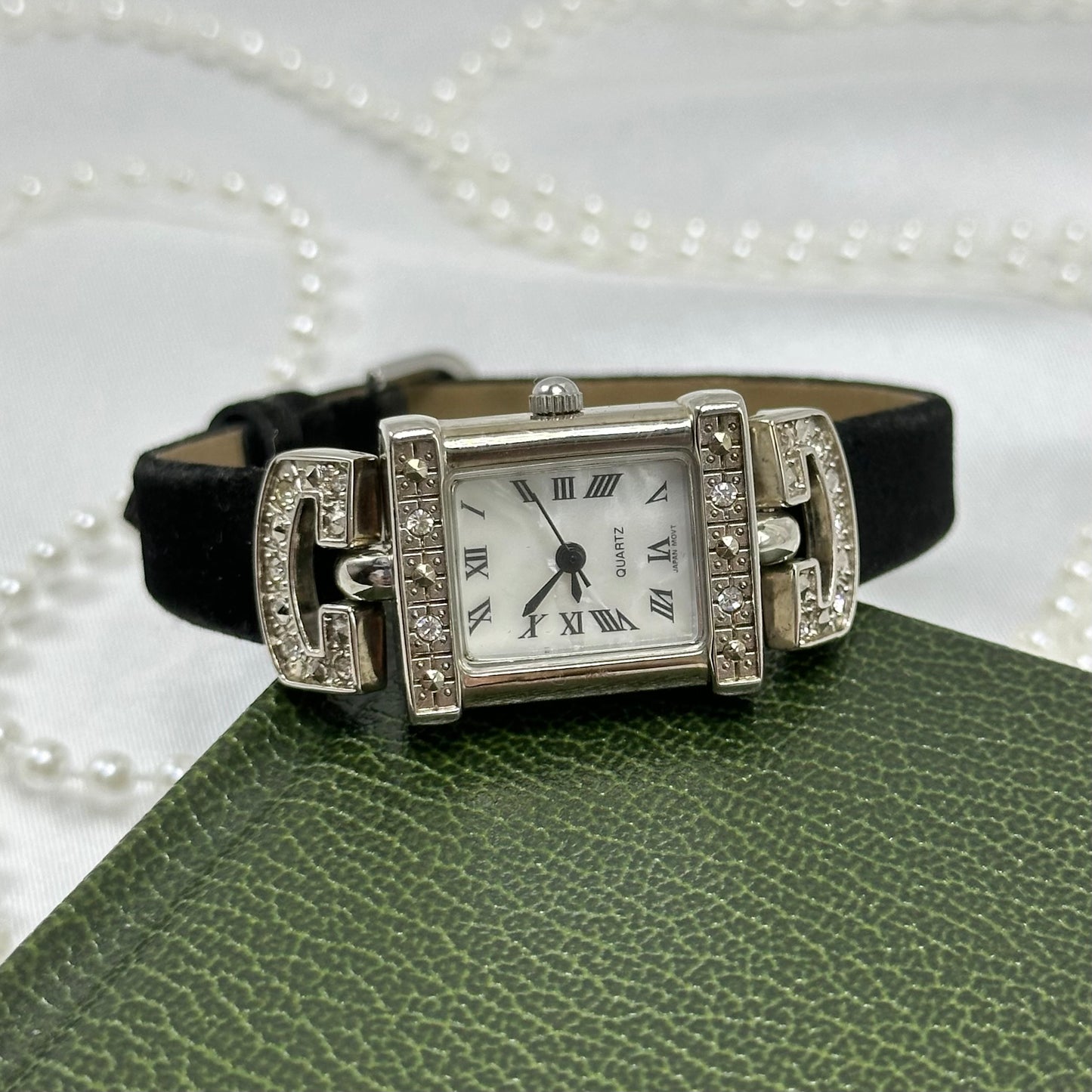 Vintage silver tone Avon watch with black velvet band and rectangular diamanté bezel.