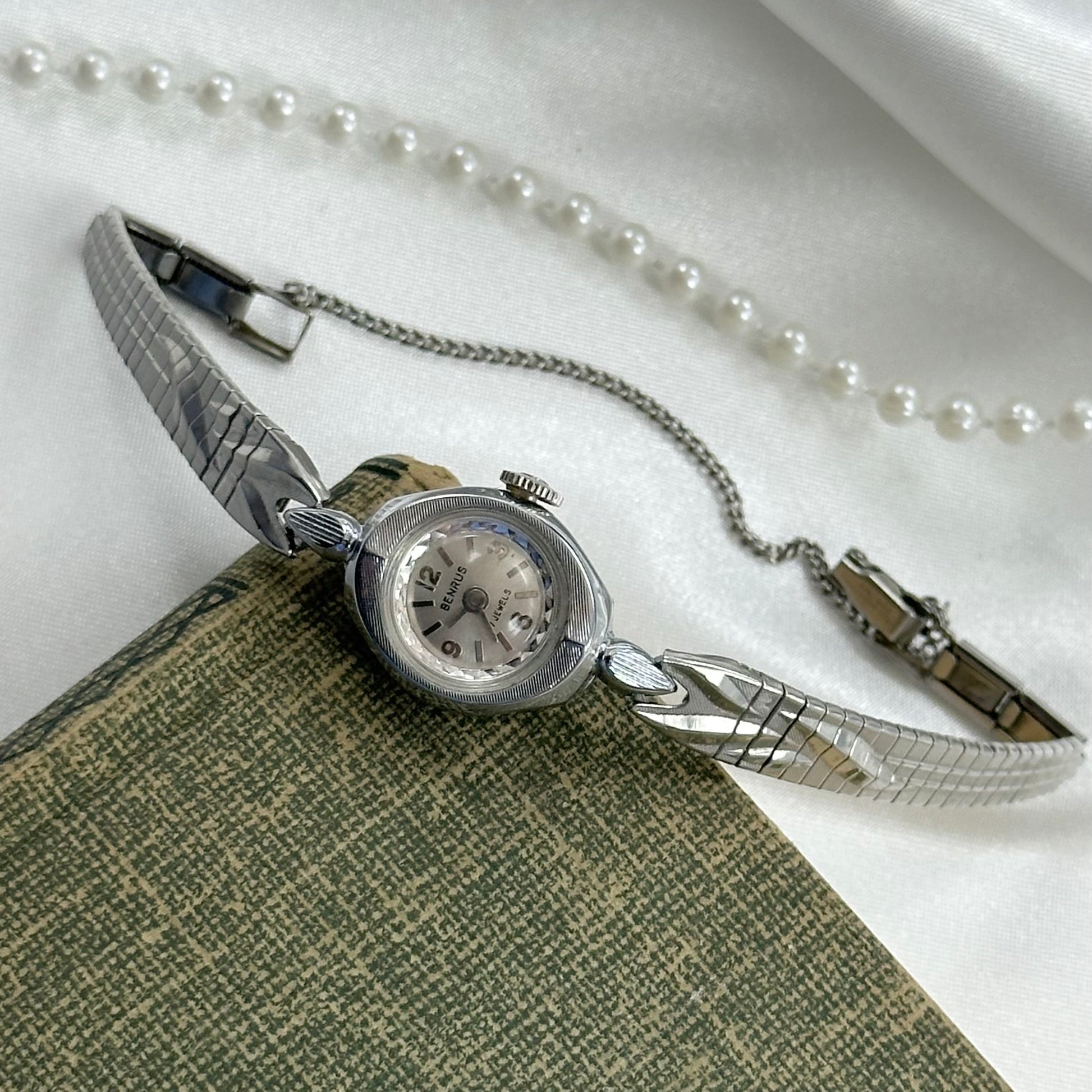 Vintage silver tone Benrus manual winding watch with detailed clasp band.