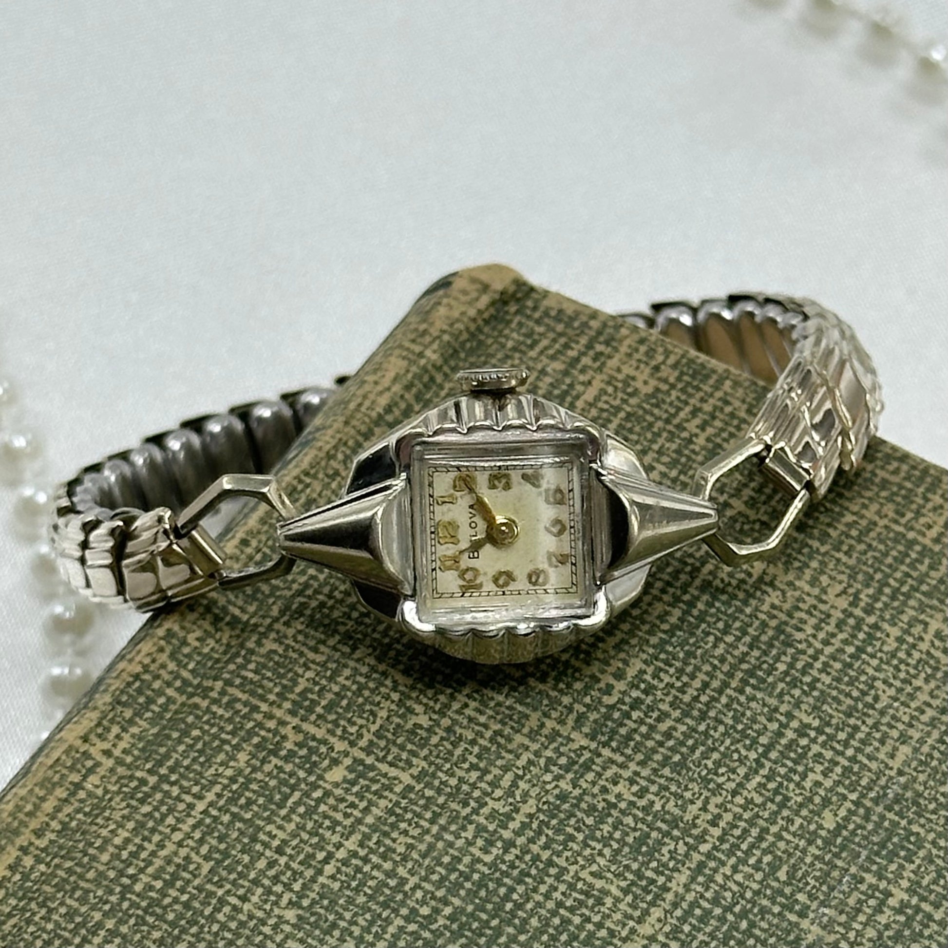 Vintage silver tone Bulova manual winding watch with gold hands and unique stretchable band from the 1950s. Watch comes with original BULOVA crown.&nbsp;