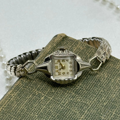 Vintage silver tone Bulova manual winding watch with gold hands and unique stretchable band from the 1950s. Watch comes with original BULOVA crown.&nbsp;