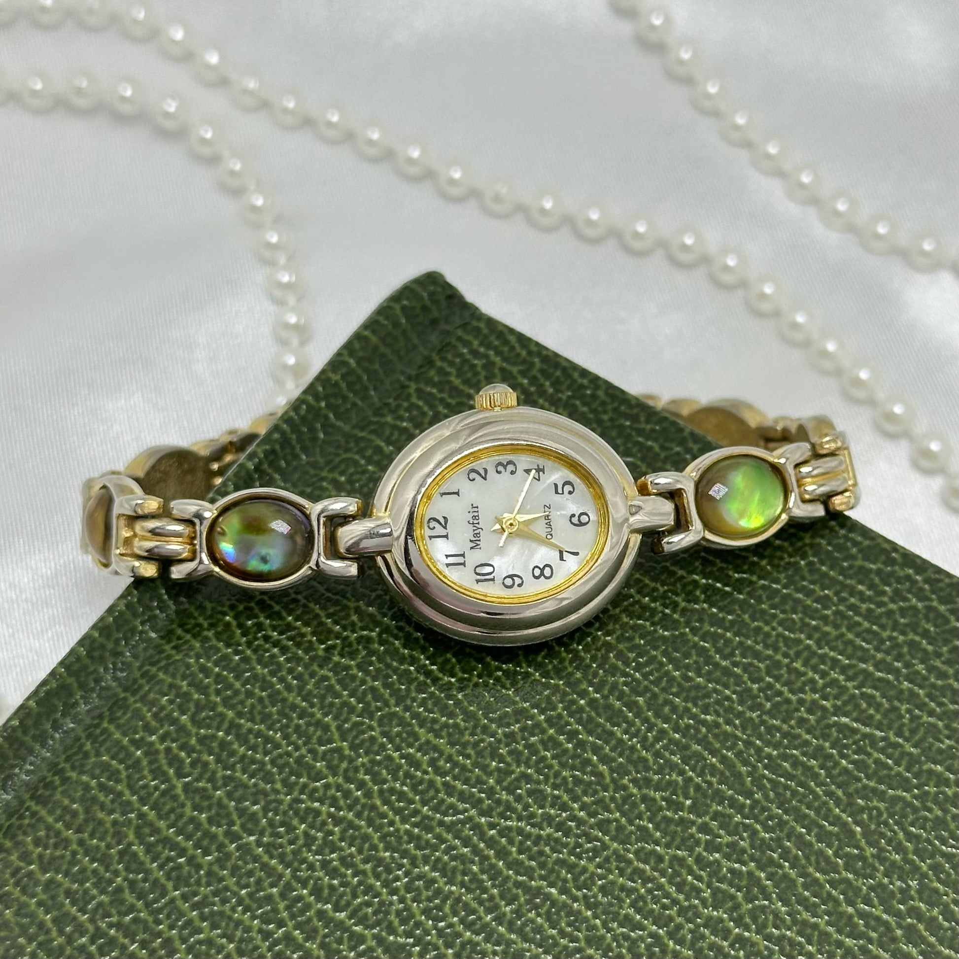 Vintage silver tone Mayfair watch with abalone clasp band and oval mother of pearl dial.