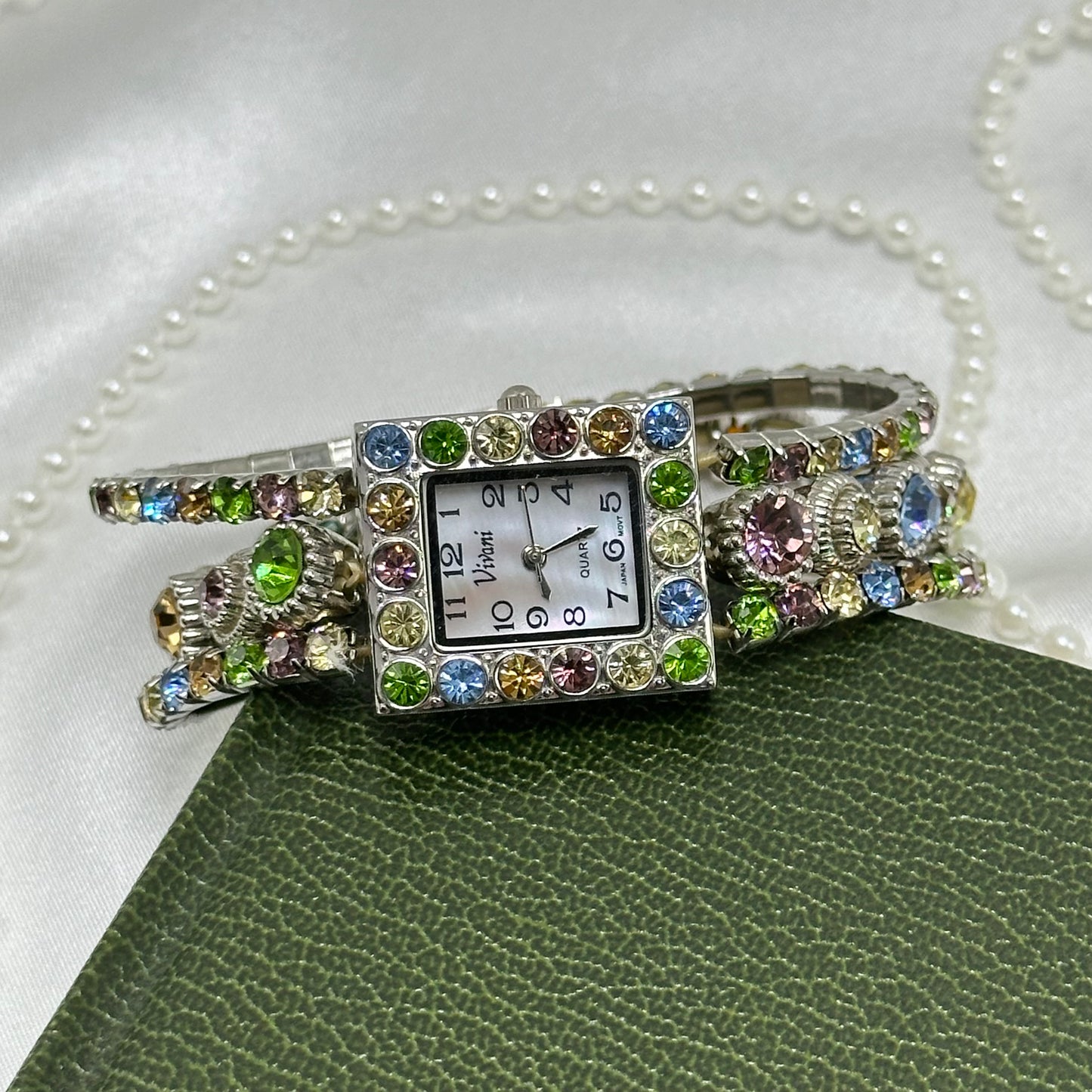 Vintage silver tone Vivani stretchy band watch with multicolor pastel rhinestones and rectangular mother of pearl dial.