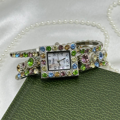 Vintage silver tone Vivani stretchy band watch with multicolor pastel rhinestones and rectangular mother of pearl dial.