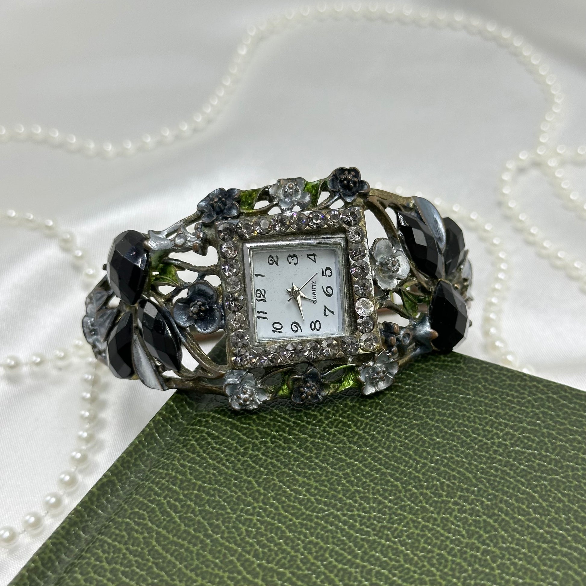 Vintage silver tone cuff watch with square diamanté dial, roses, black stones, and metal vine design.