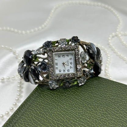 Vintage silver tone cuff watch with square diamanté dial, roses, black stones, and metal vine design.