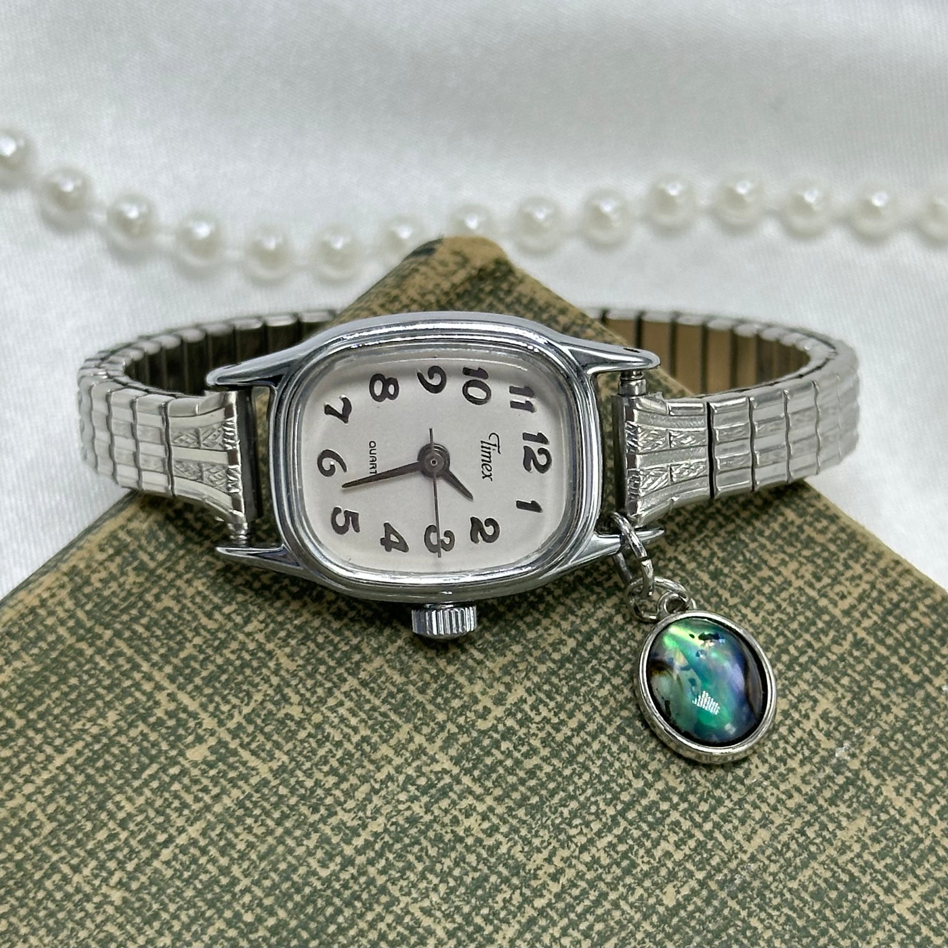 Vintage silver tone dainty Timex watch with unique dial and abalone charm.