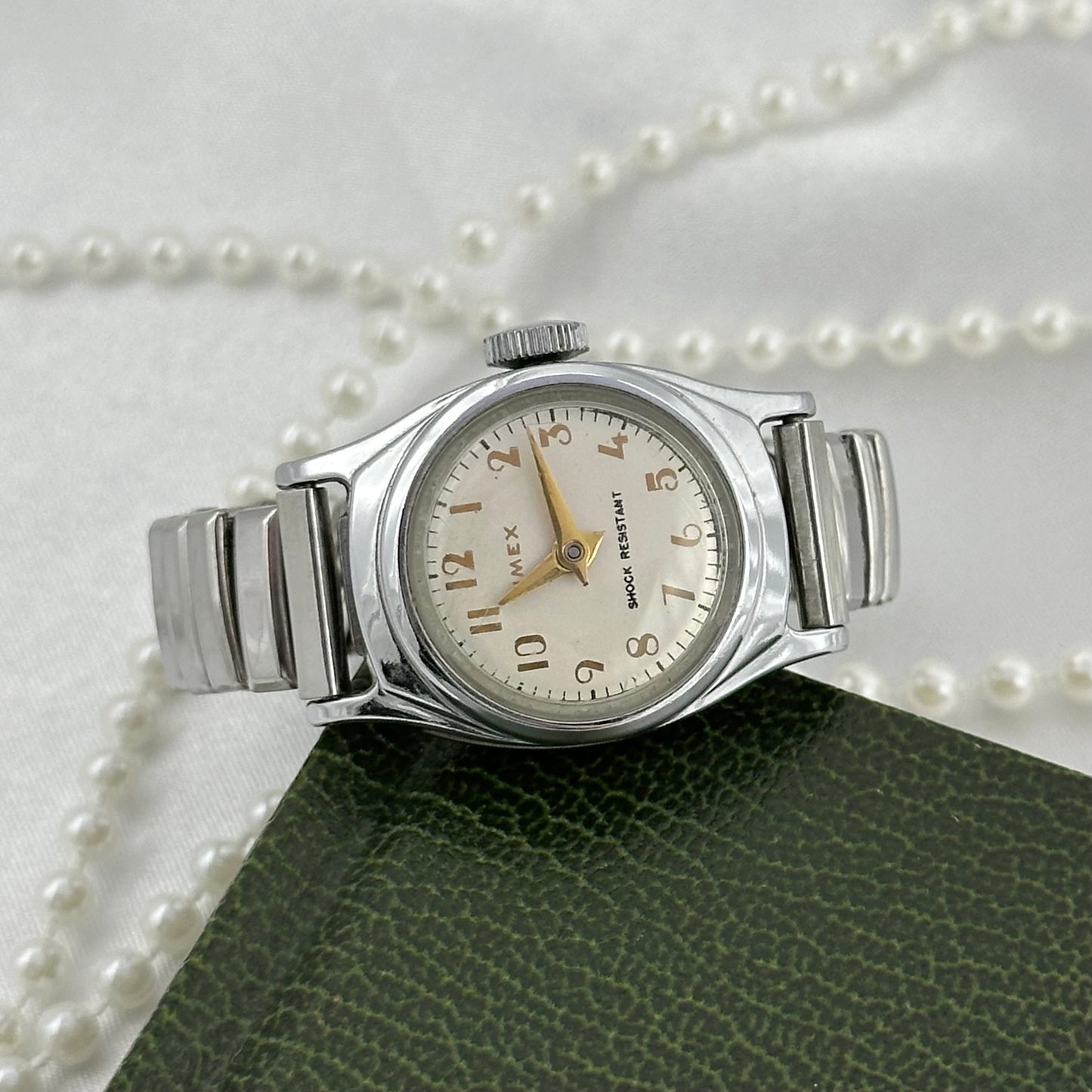 Vintage silver tone round dial Timex manual winding Swiss made watch with gold hands and markers. Band is stretchable. Shock Resistant.