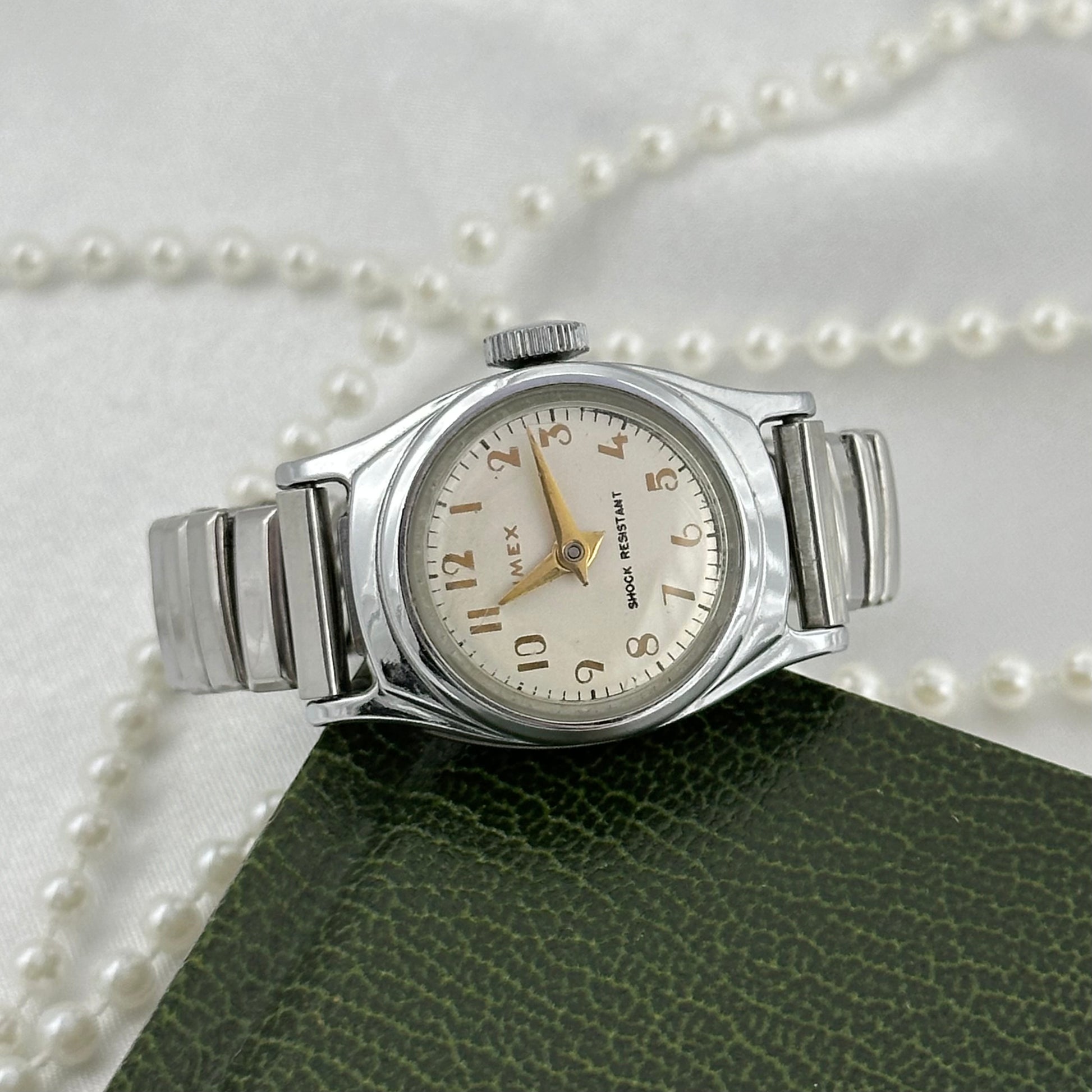 Vintage silver tone round dial Timex manual winding Swiss made watch with gold hands and markers. Band is stretchable. Shock Resistant.