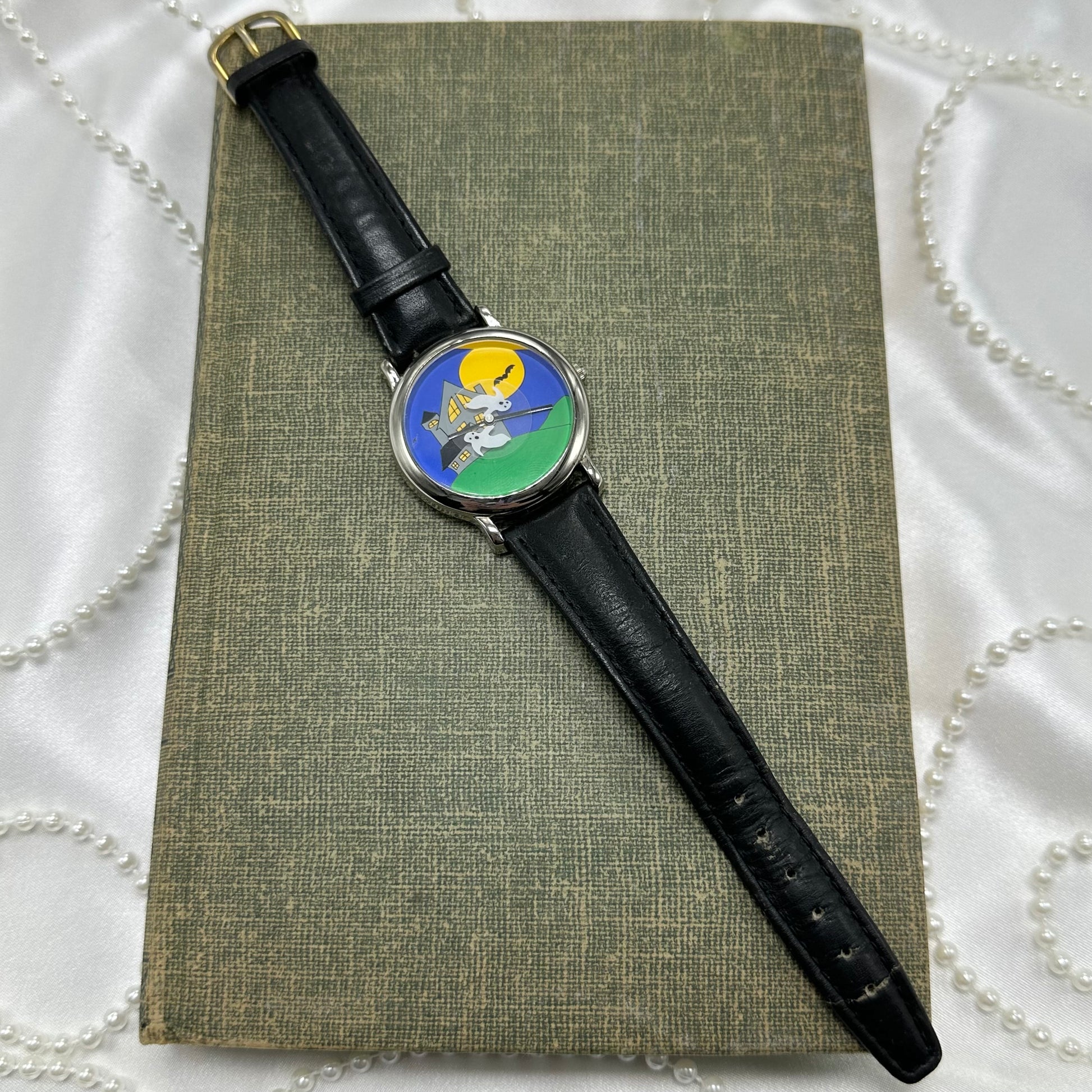 Vintage silver tone watch with unique picture of spooky ghosts and black leather band. Ghosts spin around the dial.