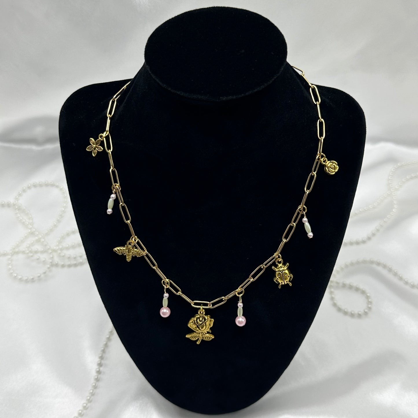 Vintage style gold tone paperclip chain necklace with whimsical bugs/flower charms and colored faux pearls.