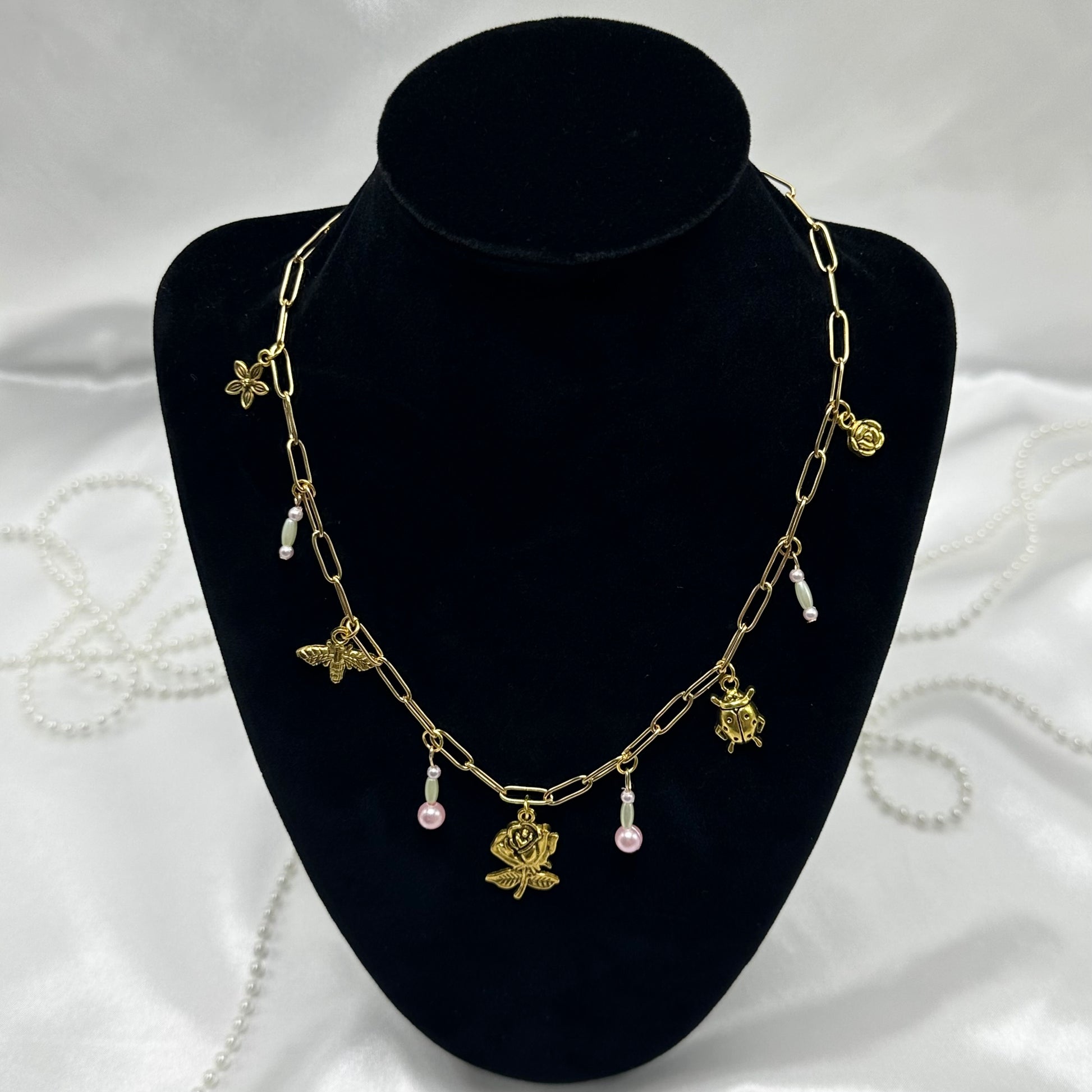 Vintage style gold tone paperclip chain necklace with whimsical bugs/flower charms and colored faux pearls.