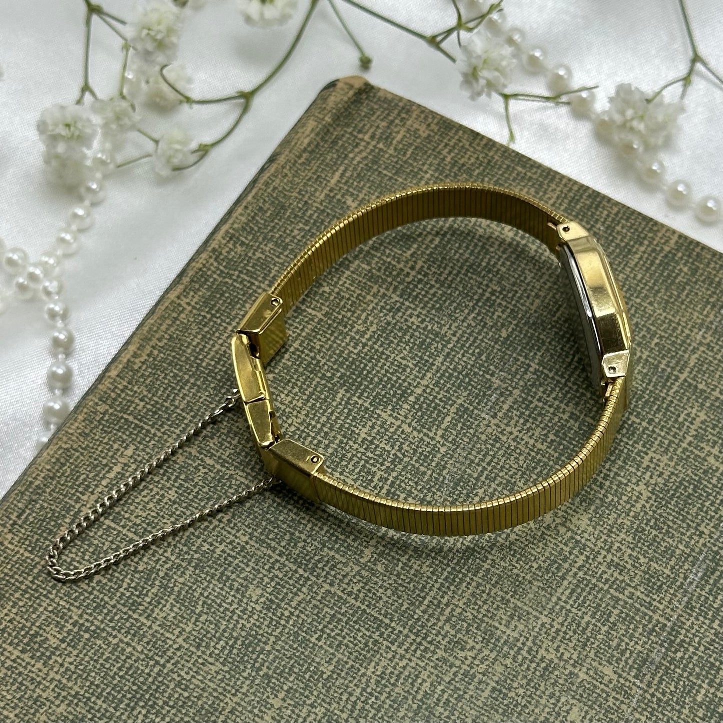 square dial Seiko watch with quartz movement and clasp band.